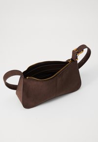 Borsa in suede marrone con forma geometrica, chiusura a zip e manico corto. Presenta accessori in metallo color oro e una superficie texture.