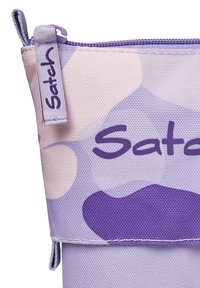 Lila gemusterte Tasche aus strukturiertem Stoff mit einem glatten Reißverschluss. Enthält das "Satch"-Logo und abstrakte Formen in verschiedenen Lila-Tönen.