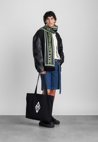 Črna usnjena jakna, bela majica, denim kratke hlače in črne teniske. Zeleno-črno vzorčna ruta. Črna torba z belo logotipom.