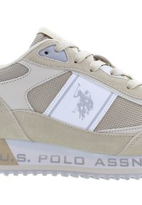 Ljusbeiga sneakers i mesh och mocka, med en vit accentpanel med en logotyp och en gummisula med grå text.