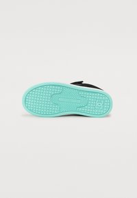 Suela de zapato negra plana con una suela exterior de color verde menta texturizada, que presenta un patrón geométrico y una impresión de logo en el centro.