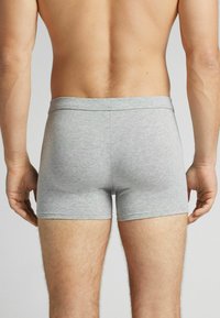 Shorts en coton gris avec une taille élastique, design ajusté et texture lisse, vus de dos sans motifs supplémentaires.