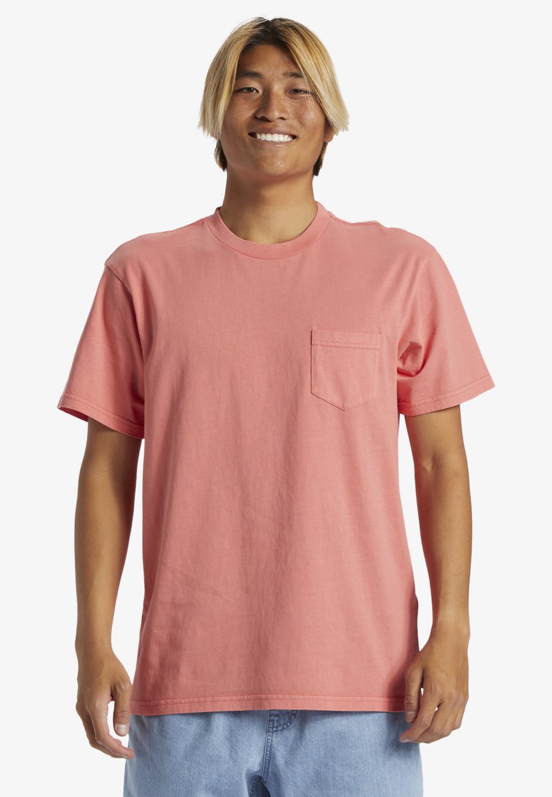 Růžové tričko z bavlny s krátkým rukávem, nabízející kulatý výstřih a náprsní kapsu. Materiál působí hladce a má volný střih.