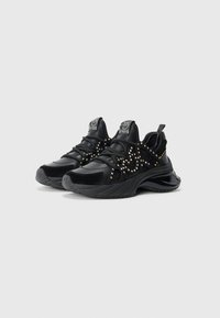 Zwarte sportieve schoenen van een mix van leer en suede. Voorzien van decoratieve gouden studs, gestructureerde details en een dikke, sculpted zool.