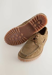 Braune Wildlederschuhe mit runder Zehenform, kontrastierendem weißen Nähten und einer gummierten Profilsohle. Verfügen über Schnürsenkel und seitliche Belüftungsdetails.