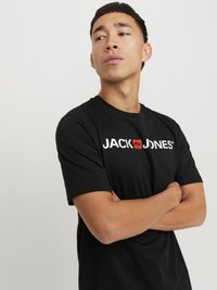 Zwarte t-shirt met korte mouwen featuring het logo "JACK & JONES" in wit en rood, met een ronde halslijn en een relaxte pasvorm. Soepele katoenstructuur.