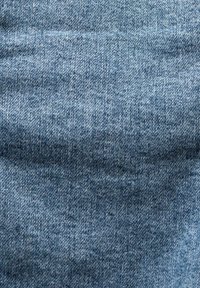 Denimtyg i ljusblått, med en slät yta och subtilt twillmönster, har små variationer i nyans över ytan.