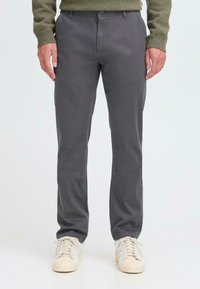 Grå bomullsblandingsbukser med slim fit, med knappefeste og lommer. Kombinert med kremfargede sneakers.