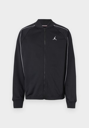 Czarna sportowa kurtka z gładkiego materiału, z białym obszyciem, zamkiem z przodu i małym logo na lewej piersi.