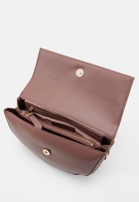 Mediumstor, rosa läderhandväska med platt design, guldhardware och tryckknappslås. Har flera fack och en slät yta.