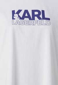 Weißes Baumwoll-T-Shirt mit fettem, dunkelblauem Text "KARL LAGERFELD" und einer Profilgrafik einer Figur im Logo-Design.