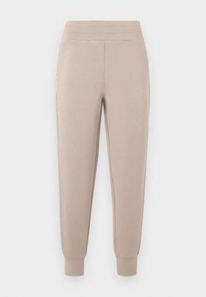 Pantaloni jogger bej din material moale, cu croială slim, talie elastică și dungi laterale cu un luciu subtil. Detaliu cu logo în față.