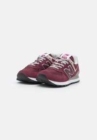Bordó velúr sneaker fehér díszítéssel, fekete gumitalppal, szürke cipőfűzőkkel és logóval az oldalon és a nyelvén. Klasszikus dizájn.