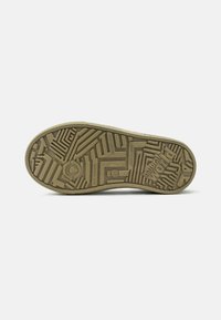 Soletta di scarpa in gomma marrone con un motivo di battistrada simile a un labirinto, con la scritta "eco friendly" e "sostenibile" impressa sulla superficie.
