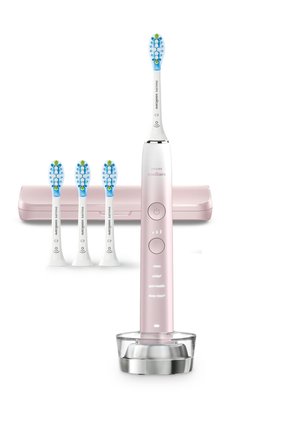 Brosse à dents électrique avec un manche rose, des accents chromés et une base de chargement transparente ; comprend trois têtes de brosse bleu et blanc.