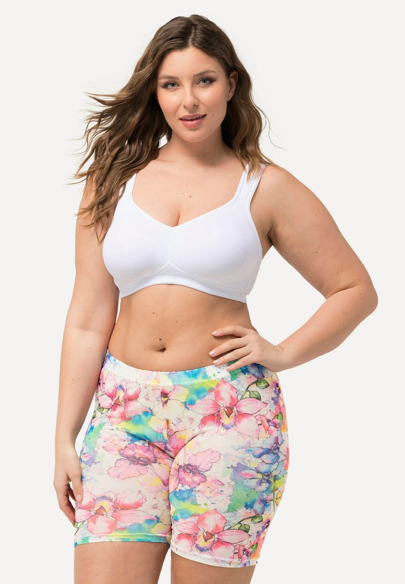 Witte sport-bh met brede bandjes, gecombineerd met legging met een multicolor bloemenprint met roze en blauwe accenten en een getailleerd ontwerp.