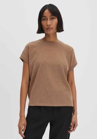 T-shirt marrone a coste con maniche corte, scollatura rotonda e vestibilità rilassata. Realizzato in tessuto texturizzato, abbinato a pantaloni neri.