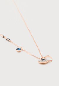 Κολιέ με αλυσίδα από ροζ χρυσό και μενταγιόν που διαθέτει μια μπλε πέτρα περιτριγυρισμένη από μικρά διαυγή κρύσταλλα, καθώς και μια μικρή μπλε σταγόνα πολύτιμου λίθου στην αλυσίδα.
