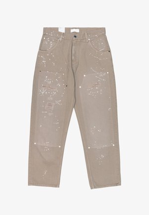 Beige Hose mit vorderen aufgesetzten Taschen, Farbspritz-Design und Gebrauchsspuren an Oberschenkeln und Knien, mit Gürtelschlaufen und Knopfverschluss.