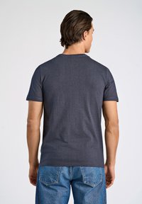 Camiseta de manga corta azul marino de algodón, con escote redondo y dobladillo recto, mostrada en un modelo de espaldas.