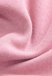 Tissu tricoté rose clair avec une texture fine, présentant une surface douce et lisse ainsi qu'une légère élasticité. Aucun motif ou accent distinct visible.