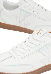 Baskets blanches avec des accents irisés et un logo pailleté. Semelle en caoutchouc, bout rond, design à lacets plats, détails texturés sur les côtés.