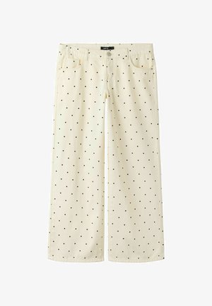 Pantalones anchos color crema con lunares negros, botón en la parte delantera, cremallera, trabillas para cinturón y dos bolsillos delanteros.