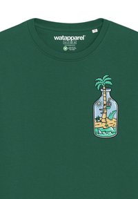 Grünes T-Shirt mit einem bunten Grafikdesign eines Palmenbaums und einer Insel in einer Flasche auf der linken Brustseite. Baumwollstoff, runder Halsausschnitt.