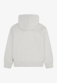 Sweat à capuche blanc avec cordon de serrage, poignets et ourlet côtelés, fabriqué en tissu doux, avec une étiquette logo sur le côté gauche près de l'ourlet.