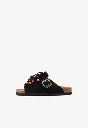 Sandalo nero slip-on con suola in sughero, cinturino regolabile con fibbia dorata e decorazioni con perline di legno colorate sulla parte superiore.