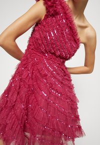 Robe fuchsia avec volants superposés et paillettes, dotée d'un design asymétrique à une épaule et d'une finition en tissu texturé transparent.