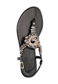 Black sandal with decorative rhinestones, featuring a flat sole, T-strap design, and adjustable ankle buckle. Smooth texture throughout.