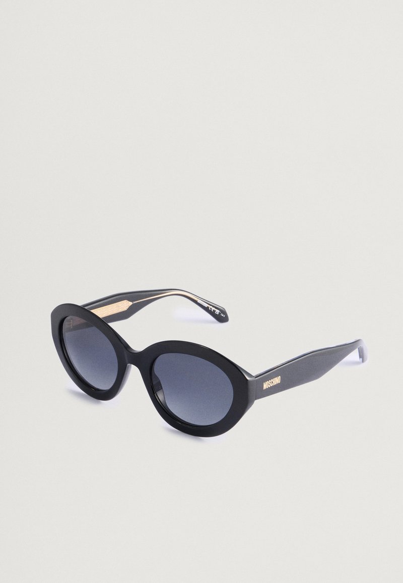 Μαύρα γυαλιά ηλίου cat-eye με γκρι φακούς gradient, με μα�τ φινίρισμα, χρυσές λεπτομέρειες στους βραχίονες και λεία υφή.