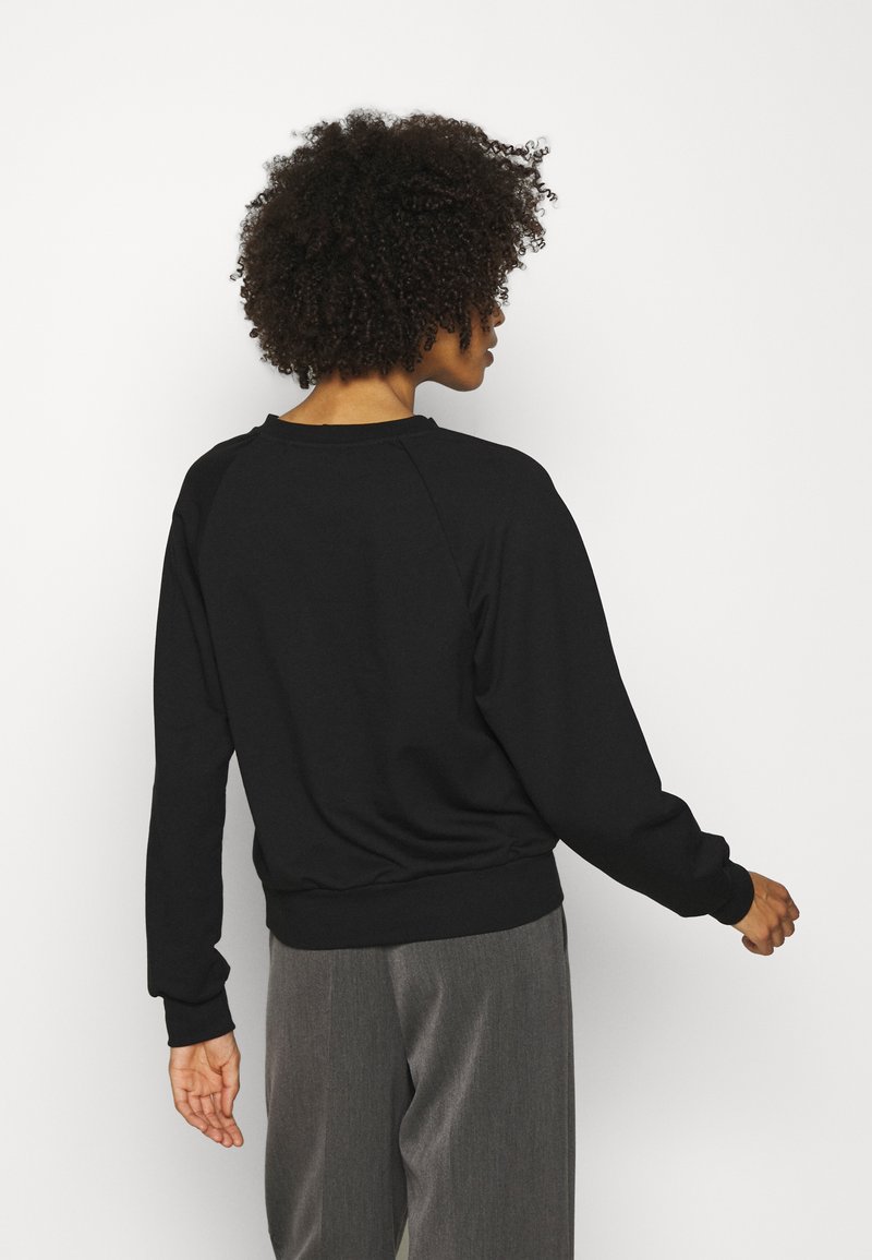 Sweat-shirt noir avec des manches raglan, des poignets et un ourlet côtelés. Tissu doux en mélange de coton, design simple, la vue arrière montre une silhouette ajustée.
