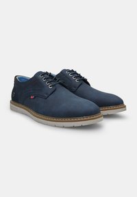 Pantofi din piele bleumarin cu un finisaj neted, având bot rotund, cusături subtile, talpă bej și un accent decorativ pe lateral.