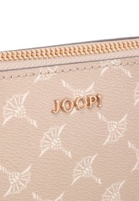 Portafoglio in pelle beige testurizzata con hardware dorato, caratterizzato da un motivo sottile e logo stampato "JOOP!" vicino alla zip.