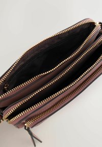 Cartera con cremallera en color malva, con tres compartimentos con cremalleras doradas, superficies texturizadas y forro interior negro.