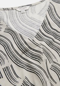 Light beige fabric with black wavy lines and a V-neck collar, showing a "Cellbes of Sweden" label with size 38/40.