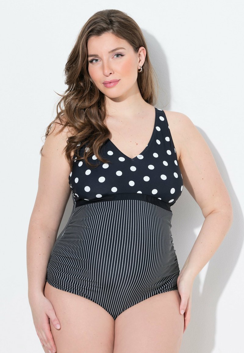 Zwarte tankini met een polkadot-top en een verticaal gestreepte onderkant, gemaakt van een soepele stof met een V-hals ontwerp.