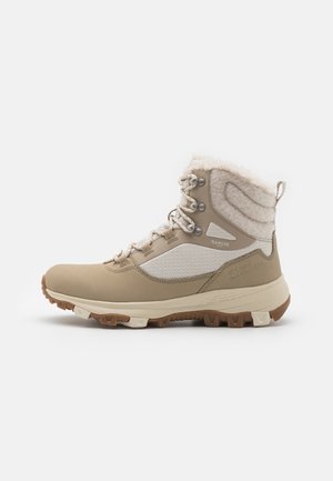 Scarpe da trekking beige alte con colletto in lana testurizzata, dettagli in rete bianca e suola in gomma resistente, dotate di occhielli in metallo e lacci.