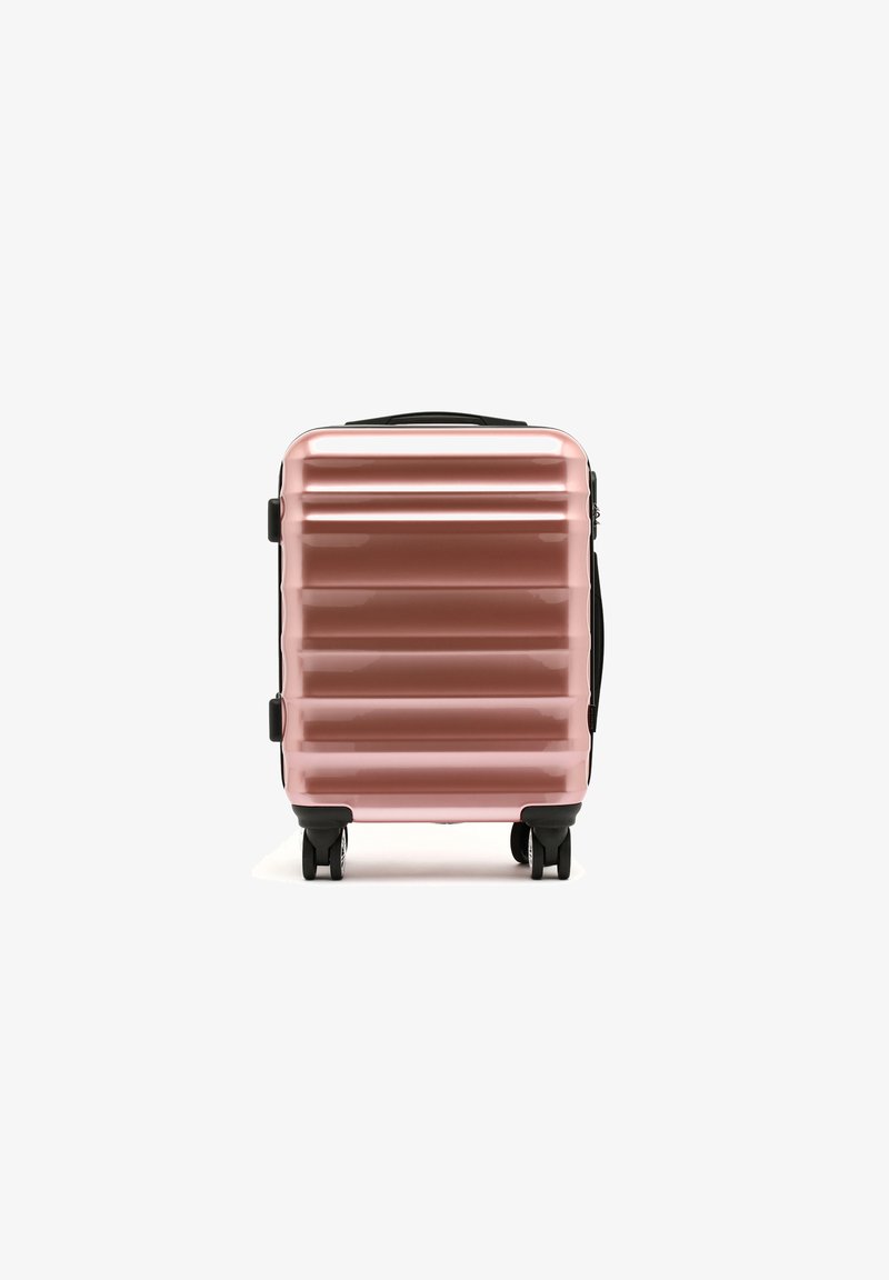 Tvrzený kufr v metalické růžové barvě, s rýhovaným designem, černými akcenty, dvěma kolečky a horní rukojetí pro snadnou přenosnost.