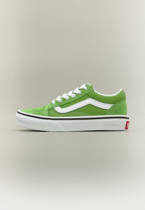 Basket basse verte avec lacets blancs, bande latérale blanche et semelle blanche épaisse avec bordure noire sur fond neutre.