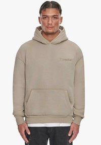 Beige hoodie med en frontlomme, justerbar sn�ørehætte og broderet "Dropsie" logo på brystet. Blød tekstur og afslappet pasform.