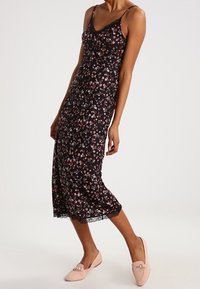 Schwarzes Blumenkleid mit Spitzenbordüre, Spaghetti-Trägern und tailliertem Oberteil. Es hat ein Blumendesign in Rosa, Weiß und Rot auf einem dunklen Hintergrund.