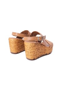 Sandali con zeppa in pelle marrone, dotati di una piattaforma in sughero testurizzato e di una cinghia alla caviglia con chiusura a fibbia. Il design è open-toe.