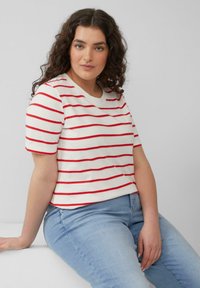 Korte mouwen witte T-shirt met rode horizontale strepen, ronde halslijn, gecombineerd met lichtblauwe jeans. Gladde katoenen stof, casual pasvorm.