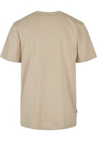 Beige puuvillane T-särk lühikeste varrukatega, ümmargune kaelus ja sile tekstuur. Omab kergelt kaardus hemmi ning ei sisalda graafikat ega kaunistusi.