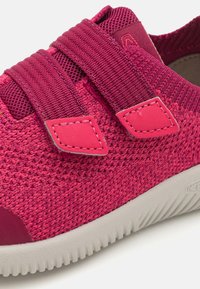 Baskets tissées roses avec deux bandes réglables, tige en tricot texturé, bout renforcé et semelle en caoutchouc avec un motif nervuré.