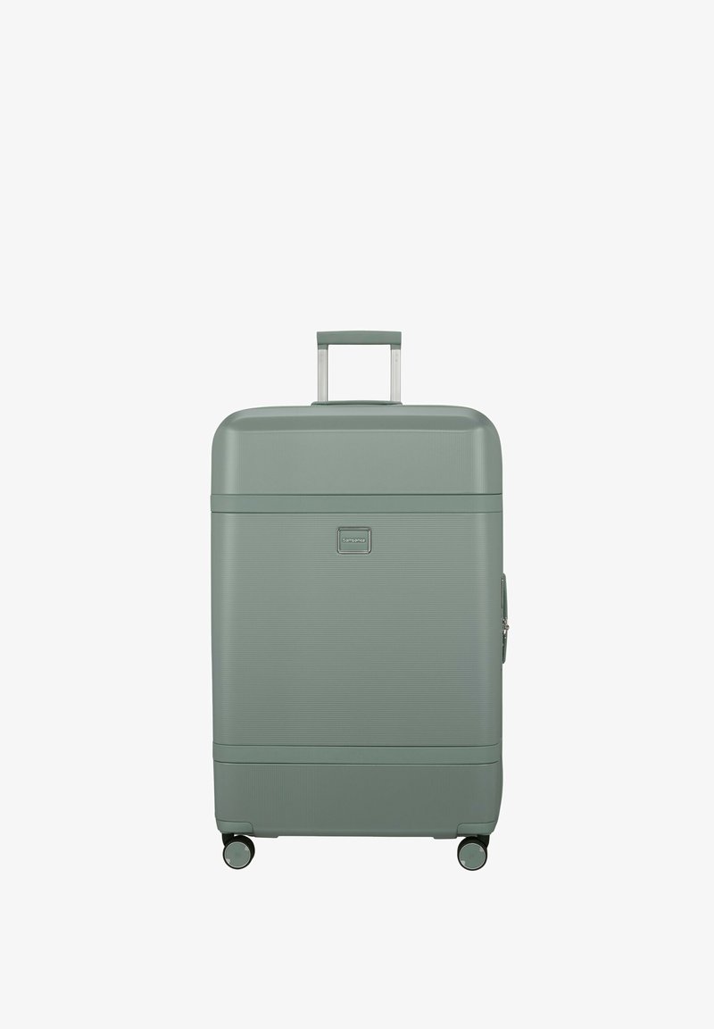 Green hard-shell suitcase with a textured surface, retractable handle, and four wheels for mobility. Features a small logo and zipper closure.