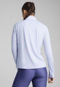 Haut de sport à manches longues bleu clair avec un col montant, texture lisse et un logo discrètement placé près de l'ourlet. Design ajusté.